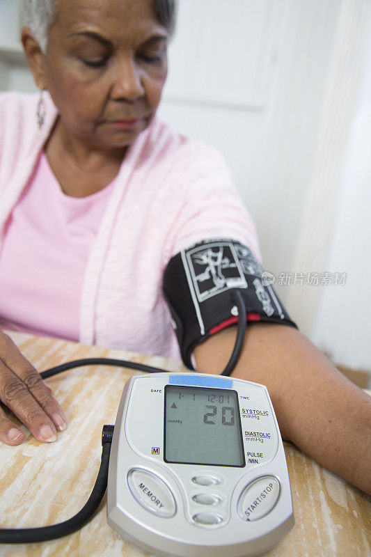 一位可爱的老年非裔美国妇女在监测她的血压。