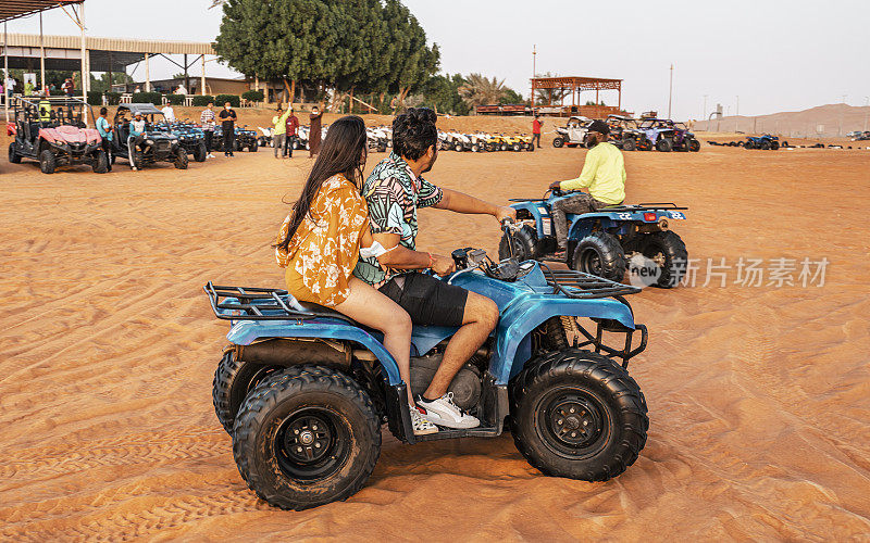 阿联酋，迪拜——快乐的四驱车在沙丘上行驶。年轻活跃的夫妇在户外活动驾驶四轮亚视沙漠，迪拜，阿拉伯联合酋长国