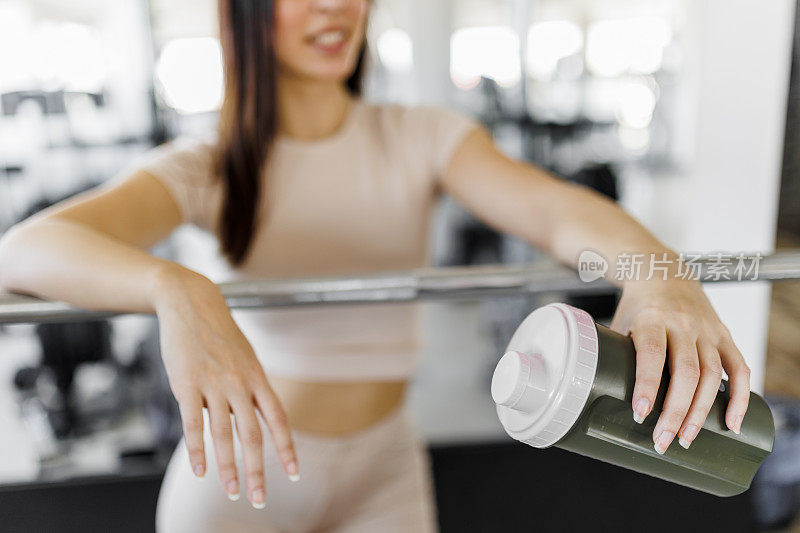 年轻女子在健身房锻炼后喝蛋白质奶昔