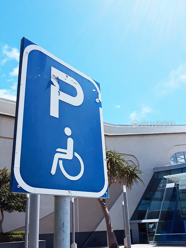 在阳光明媚的天气，建筑物外的残疾人停车标志