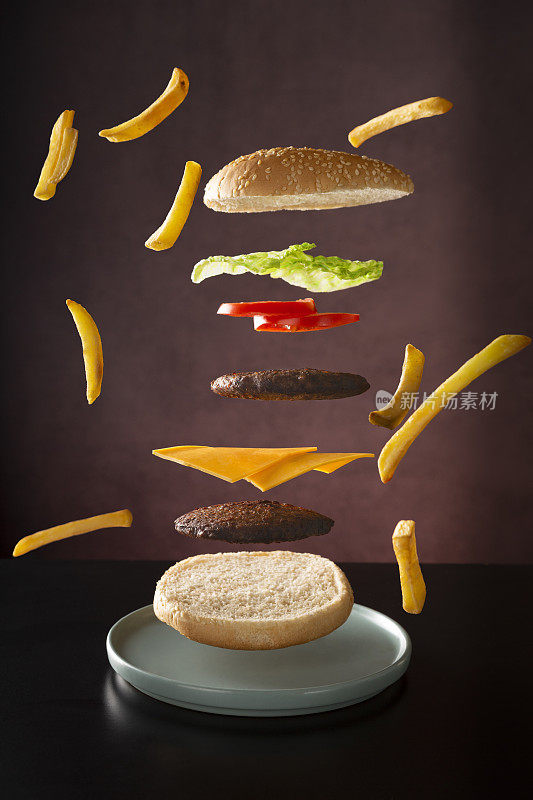 美味的双层芝士汉堡在盘子里飞来飞去，薯条在旁边
