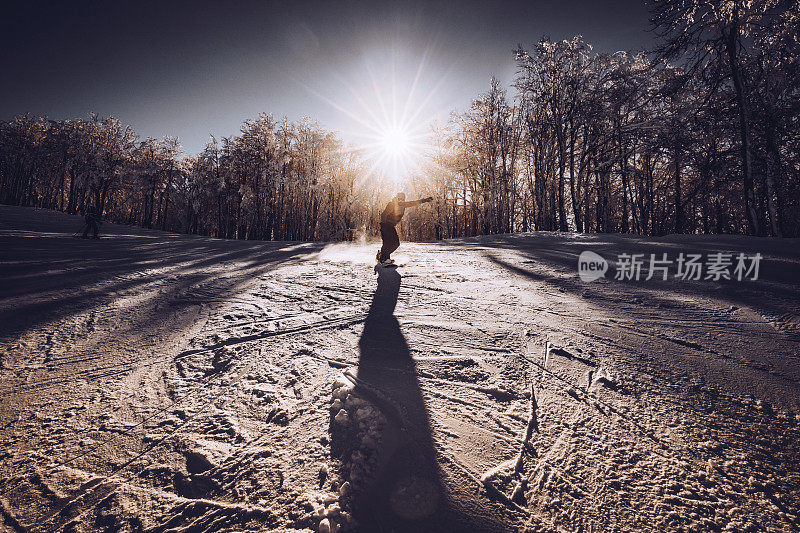 一个年轻人在冬天的白天滑雪下山。