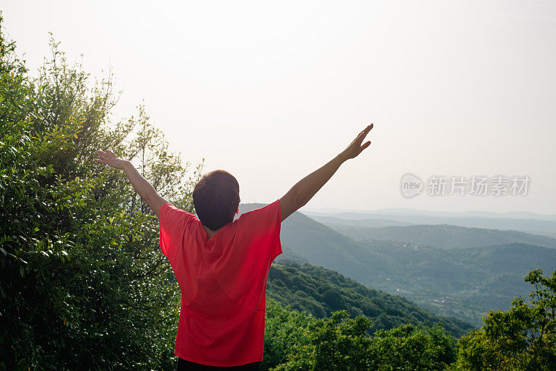 在大自然中，一个年轻的女子举起双手表示高兴。