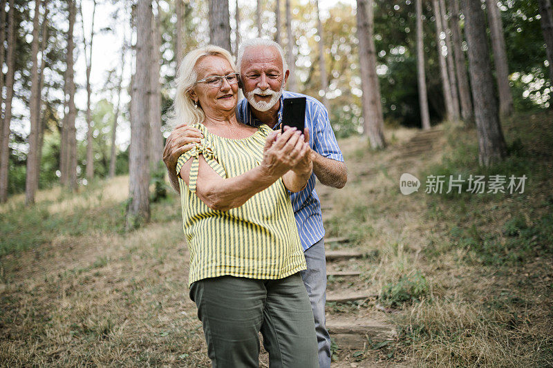 微笑老年夫妇在森林中使用手机