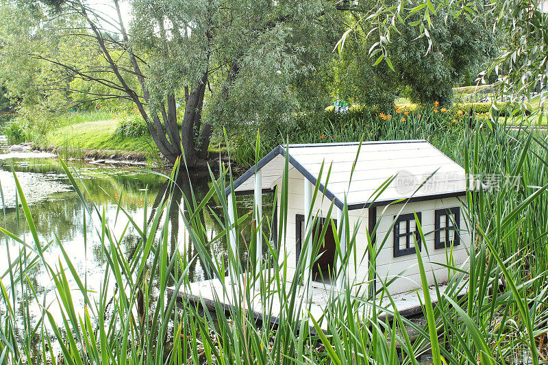 公园池塘中央的白色木制漂浮鸭子屋