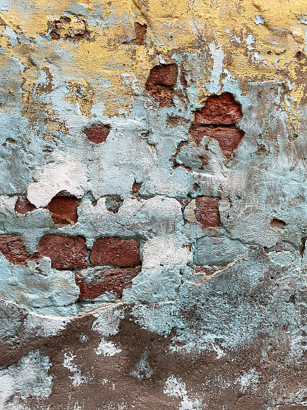 红砖墙与蓝色和金色的片状，剥落的油漆，剥落的砖石油漆，油漆层，风化，墙纸背景