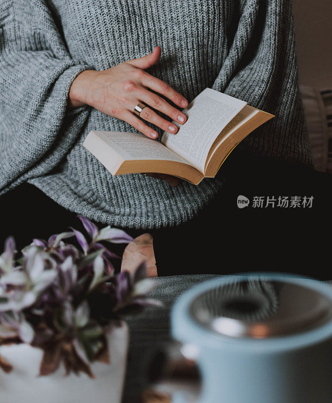 女人穿着暖和的套头衫翻着书，冬天是读书最好的季节