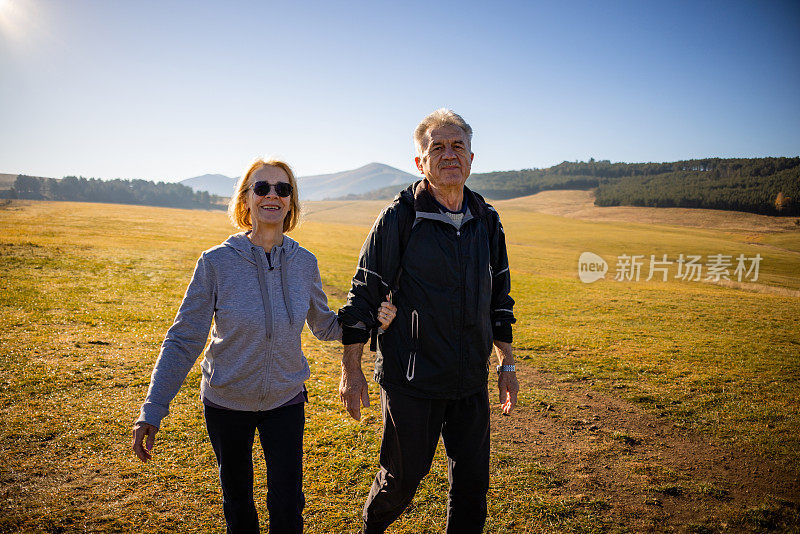 活跃的白人高级已婚夫妇，手牵着手，享受秋天远足