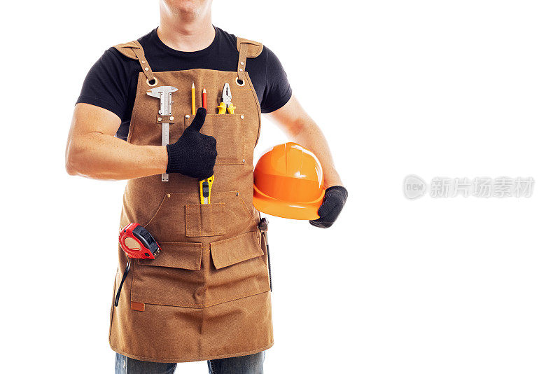 穿着围裙，带着工具和头盔，竖起大拇指的承包商工人或木匠