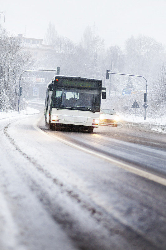 公路上的公共汽车在冬天的降雪中缓慢行驶