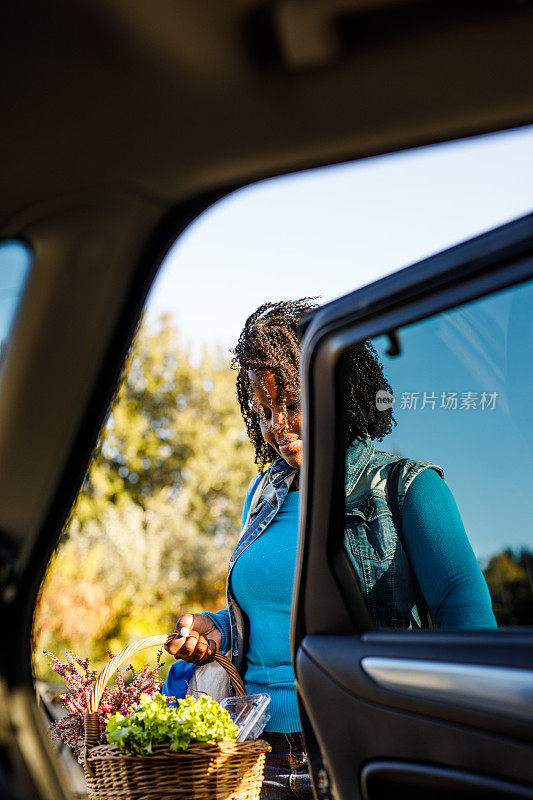 年轻女子在参观完农贸市场后，在她的汽车后座上装载杂货