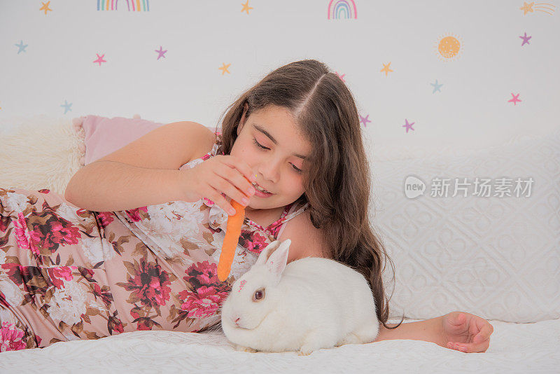 女孩躺着给兔子吃胡萝卜