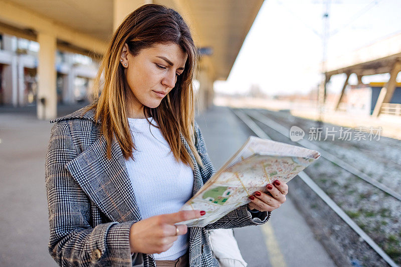 一个女人一边看地图一边等火车