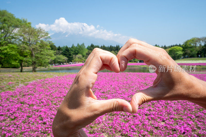 一名女子在日本旅游，她在富士山附近画了一个心形