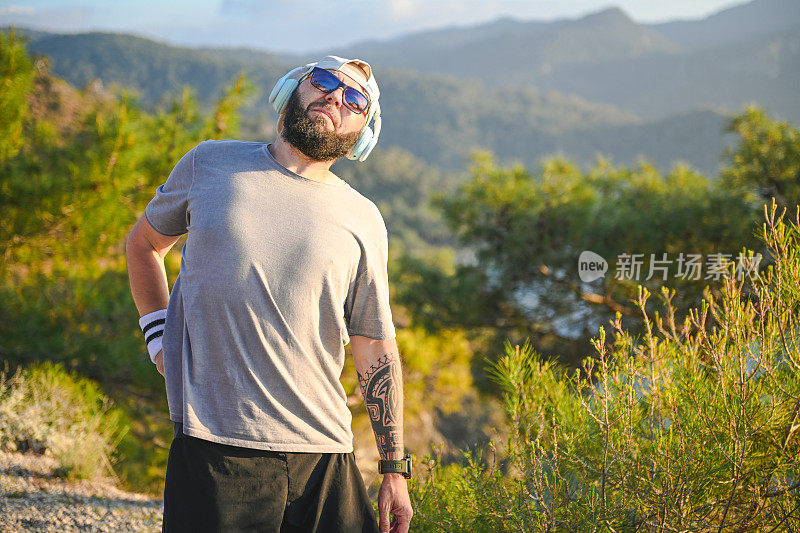 穿着运动服的男人沿着海边奔跑，可以看到群山