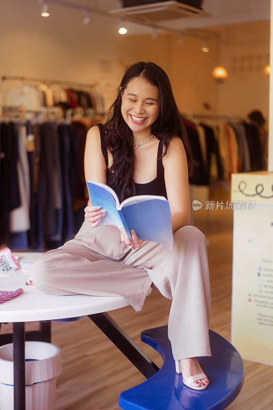 马来西亚华人妇女坐在圆桌上阅读当地旧货店的杂志