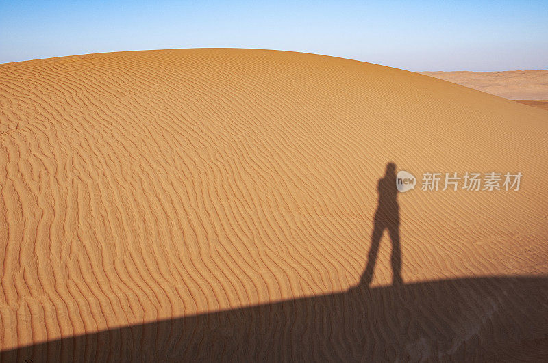 沙漠的清晨。摄影师在沙漠沙丘上的影子。