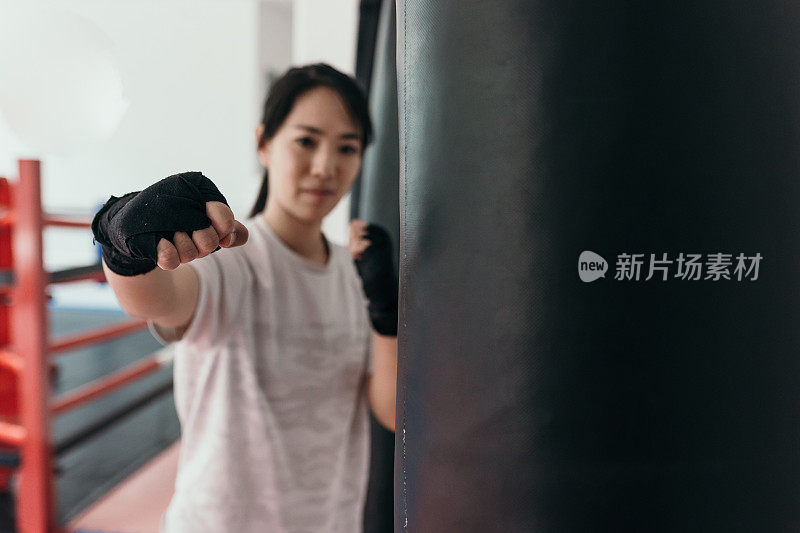 在训练馆里练习自由搏击的亚洲女子