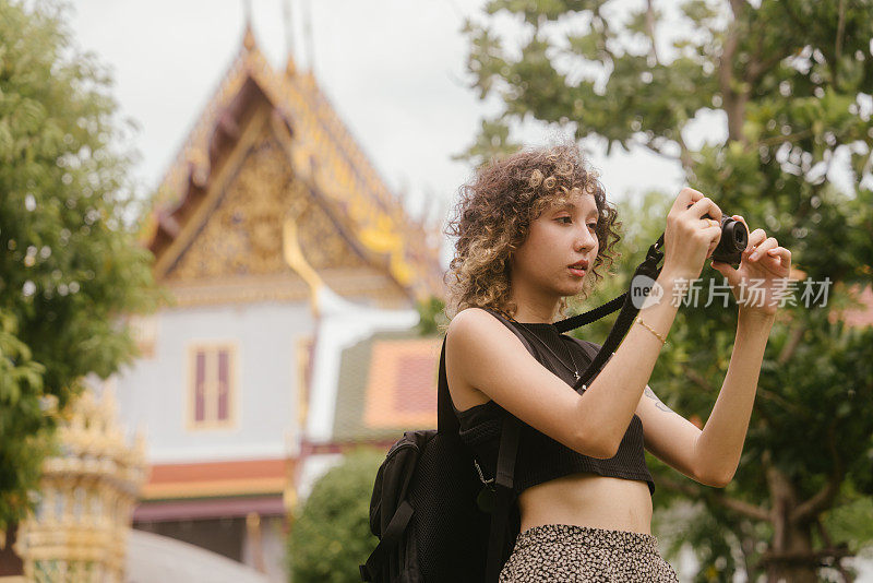 有魅力的年轻女游客夏天背包旅行，在步行街享受户外生活和拍照。