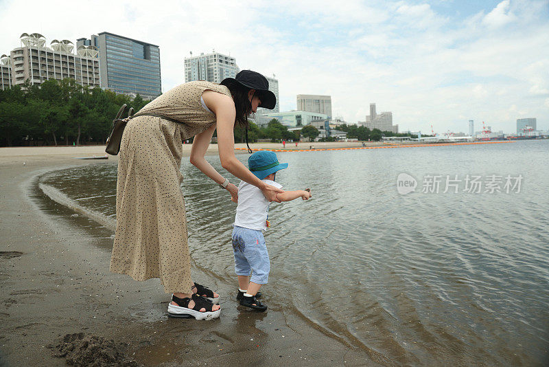 年轻的母亲带着她的小儿子在海滩上散步