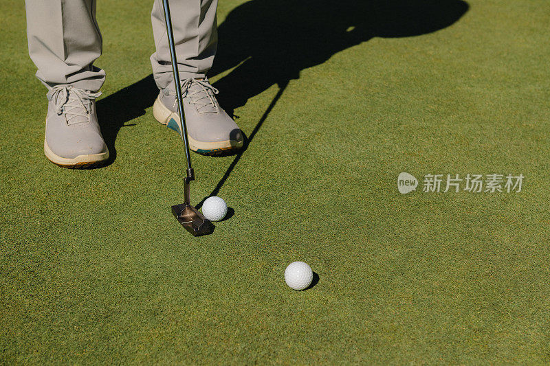 一名男子高尔夫球手的脚的细节，在绿色的草地上挥杆击球