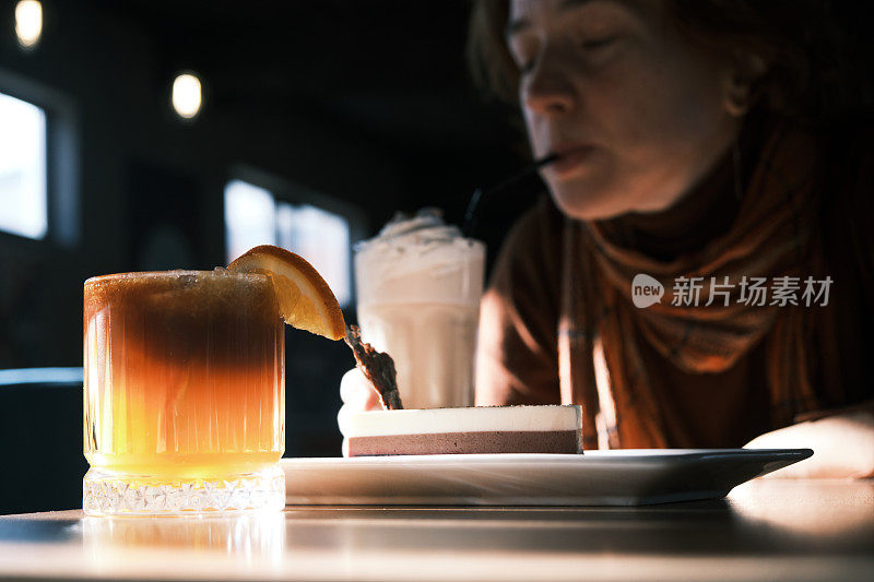 一个开朗的成熟女人坐在昏暗的咖啡馆里喝咖啡