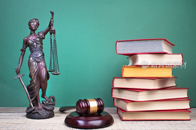 法律概念-打开法律书，法官的小木槌，天平，法庭或执法办公室桌子上的忒弥斯雕像。