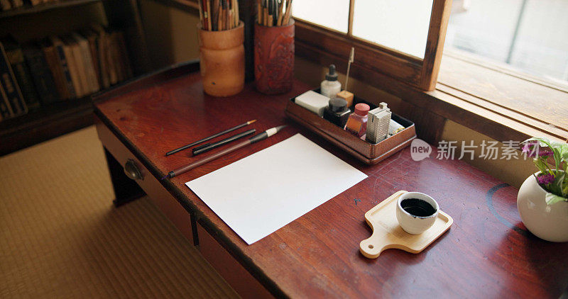 在一个家庭工作室的桌子上，有墨水、画笔和日本艺术的纸，还有创意工具。创意，画家的文书工作和艺术家的素描文件和书法与铅笔和绘画