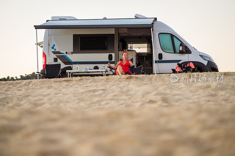 停在希腊海滩上的露营车或房车。家庭度假时，女游客开着房车在沙滩上享受和放松。