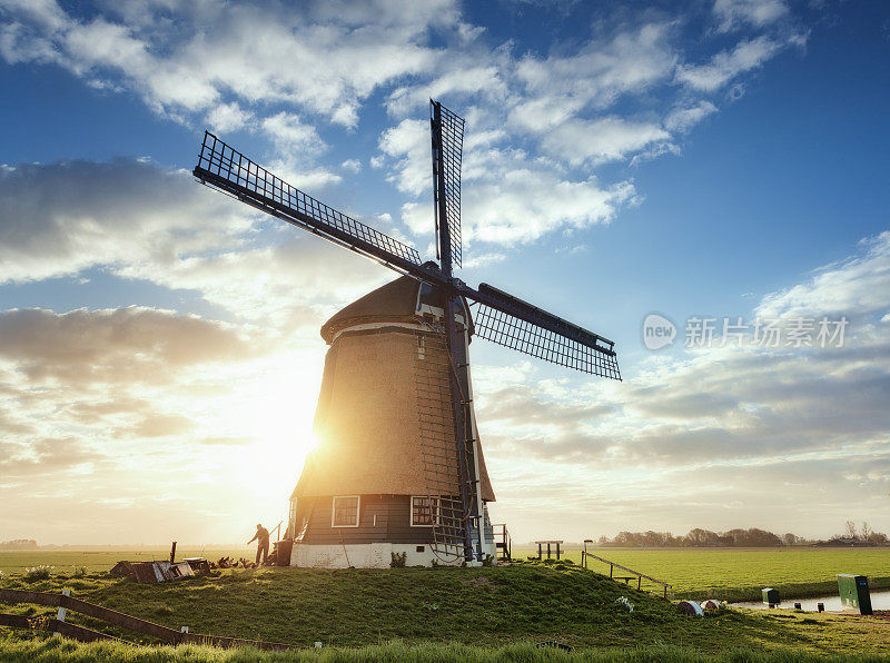 风车和一个人的剪影在日出在荷兰