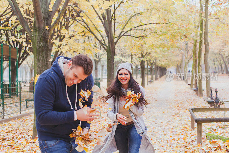 快乐的年轻夫妇在秋天的公园里玩耍