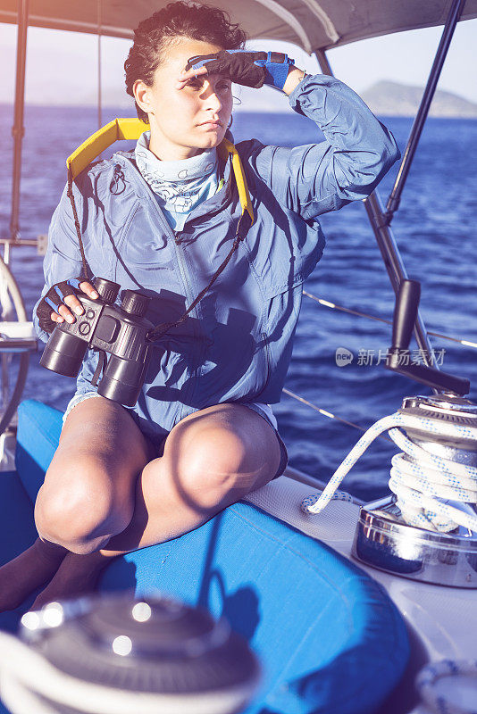年轻女子在航海，用双筒望远镜观察