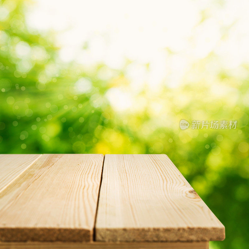 木制桌面模糊的绿色花园在早上的背景。
