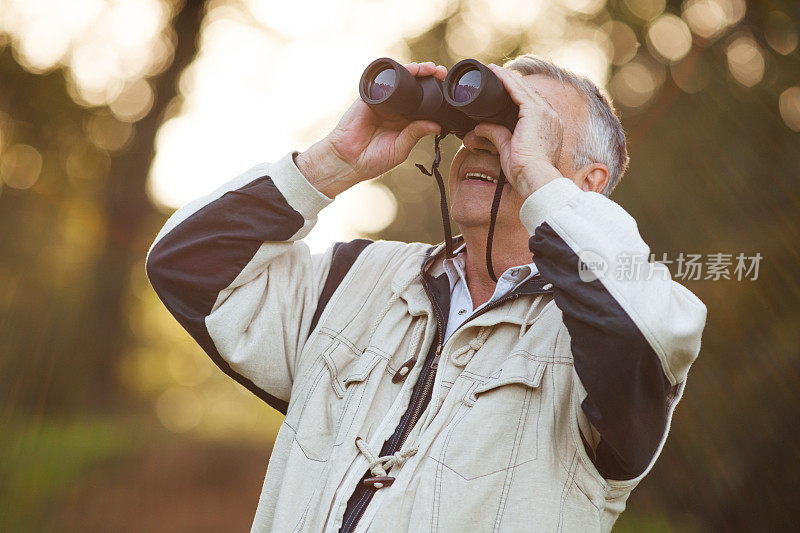 老人用双筒望远镜探索大自然