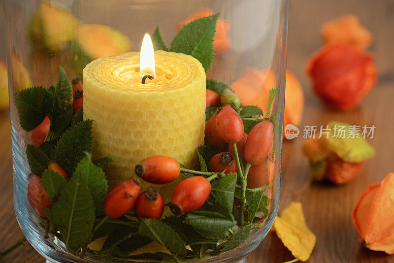 燃烧着的蜂蜡玻璃蜡烛和玫瑰果