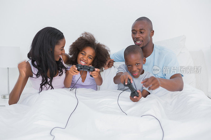 欢乐的一家人坐在床上玩电子游戏