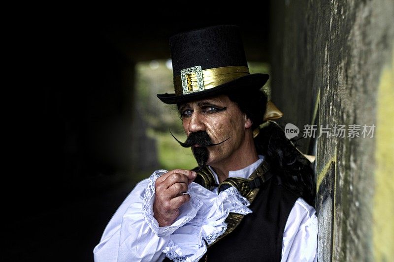 男子穿着蒸汽朋克，维多利亚时代的服装，深色的墙壁背景