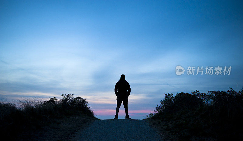 夕阳下，在小路上等待的人的剪影