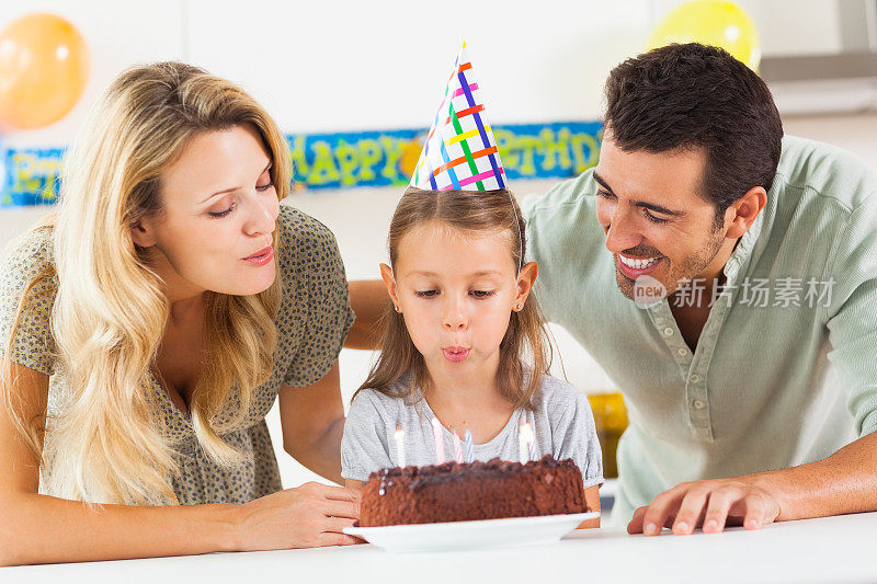 女孩在他的生日蛋糕上吹蜡烛