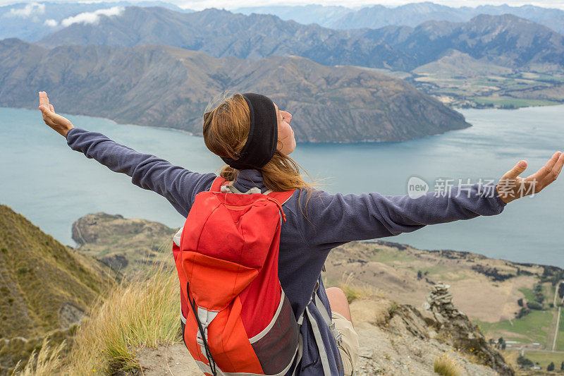 一位年轻的徒步旅行者站在山上，双臂张开