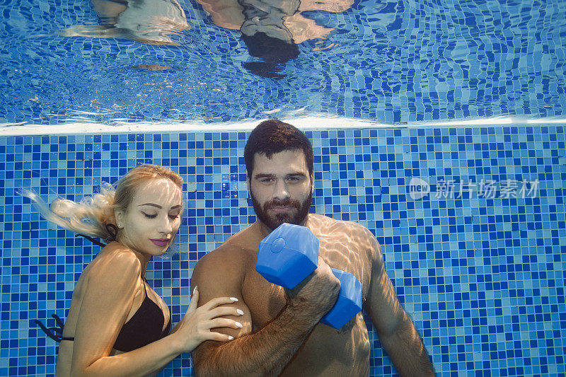 水下女子和男子在游泳池用哑铃训练