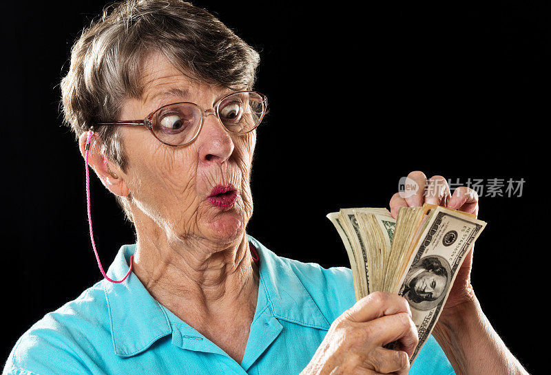 老妇人惊奇地数着厚厚的一捆美元，眼睛睁得大大的
