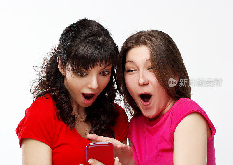 姑娘们在手机上看短信，两个快活的姑娘在用智能手机