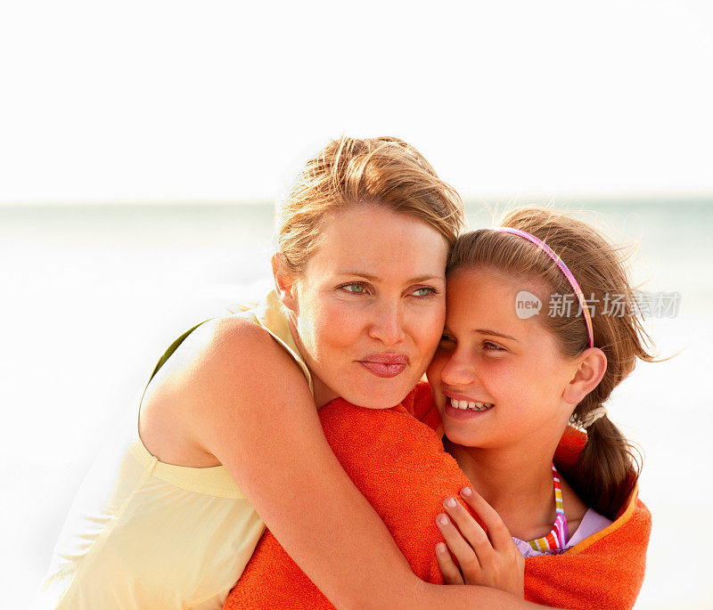 在海边，慈爱的母亲拥抱着她的女儿