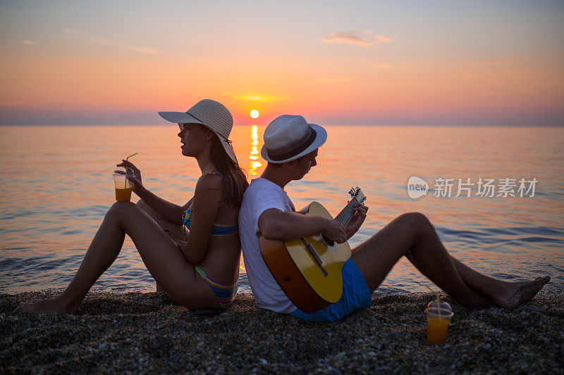 年轻的情侣们在海滩上演奏音乐，一起享受。