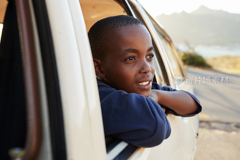 一个男孩在家庭公路旅行中向车窗外看