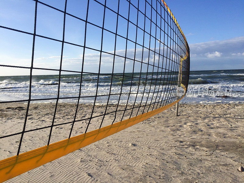沙滩排球网特写。蔚蓝多云的天空和海滩上黄色的沙子