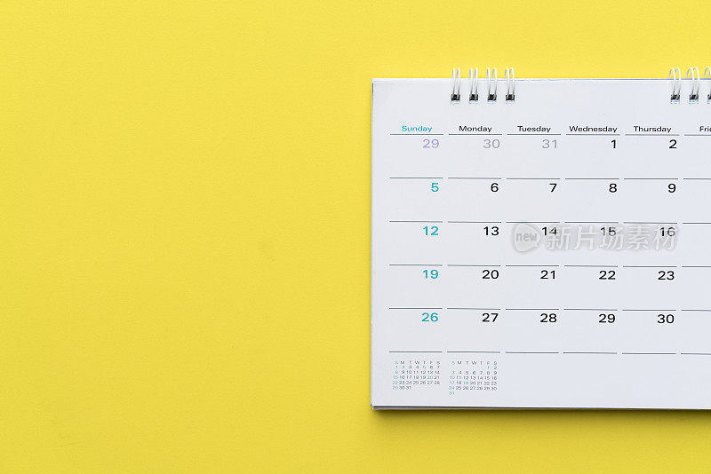 近距离的日历上的黄色背景，计划商务会议或旅行计划的概念