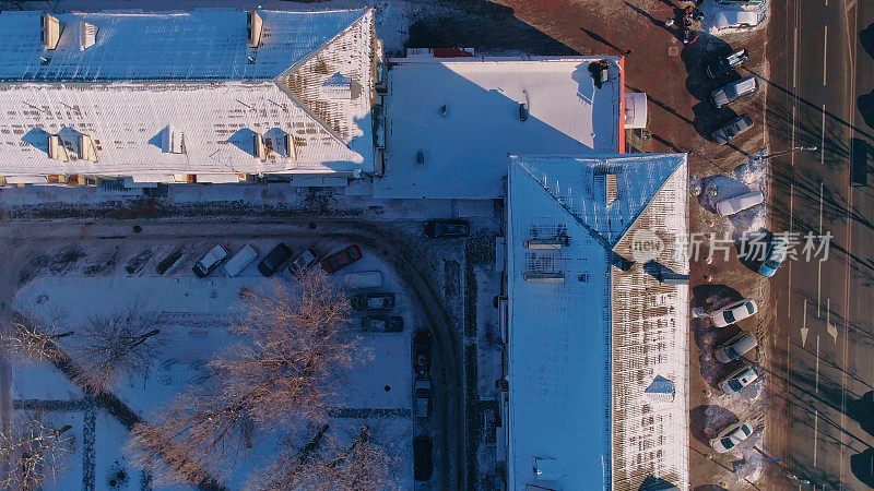 俯视图，正上方鸟瞰被雪覆盖的冬季城市住宅区。攀爬和旋转复杂的摄像机运动。