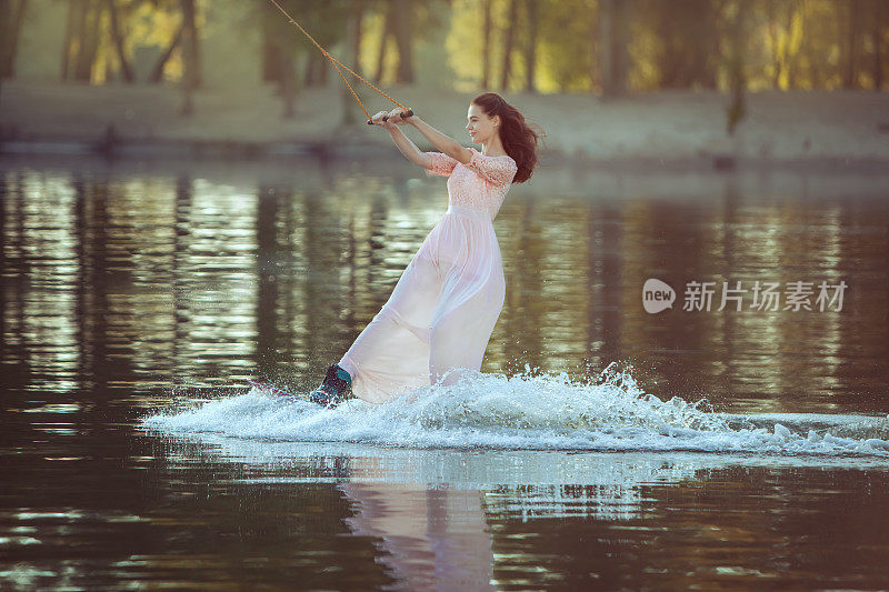 一个穿着裙子的女人正在水上公园骑车。